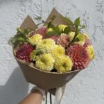 Букет из розово-желтых георгинов и крупных лимонных бархатцев в крафте